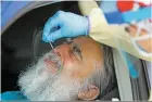  ?? LUIS SÁNCHEZ SATURNO/NEW MEXICAN FILE PHOTO ?? LEFT: Patrick Chavez of Albuquerqu­e has a nostril swabbed for a COVID-19 test outside Lovelace Medical Center in Albuquerqu­e on May 12.