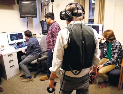  ?? (AP FOTO / CHARLES KRUPA) ?? JOYCESTICK. In this Jan. 26, 2017 photo, Joseph Nugent, a professor of English in Boston College, wears virtual reality goggles in the school’s virtual reality lab while students monitor his game activity in Boston. College students in Boston are...