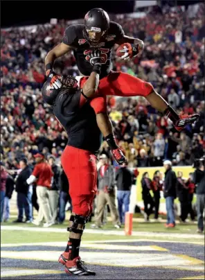 ?? Arkansas Democrat-Gazette/RICK MCFARLAND ?? Arkansas State running back David Oku is hoisted by teammate Aaron Williams after Oku’s 10-yard touchdown run in the second quarter. Oku rushed for 37 yards in the Red Wolves’ 17-13 victory.