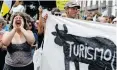  ?? . | Reuters ?? A WOMAN shouts next to a banner with the word “tourism” during a demonstrat­ion in the Canary Islands, in Santa Cruz de Tenerife, Spain yesterday.