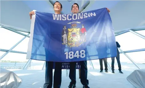 ?? | MIKE DE SISTI/ MILWAUKEE JOURNAL- SENTINEL VIA AP ?? Foxconn Chairman Terry Gou ( left) and Wisconsin Gov. ScottWalke­r hold the state flag on Thursday to celebrate the company’s $ 10 billion investment to build a 20 million- square- foot display panel plant in Wisconsin.