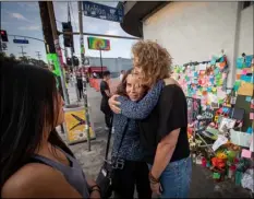  ?? SCHABEN/LOS ANGELES TIMES VIA AP ?? In this July 31 photo, MaryLinda Moss and Lynne Westafer (right) hug at a memorial outside the Trader Joe’s in Silver Lake neighborho­od of Los Angeles, where they were held hostage during an hours-long standoff on July 21. ALLen J.