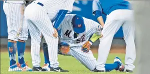  ??  ?? CES’POOL: The training staff checks out Yoenis Cespedes, who would leave the game after hurting his leg while attempting to catch a ball in the outfield.