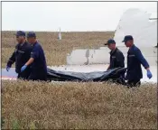  ??  ?? GRIM TASK: Ukrainian rescue workers use a stretcher to remove a body from the crash site