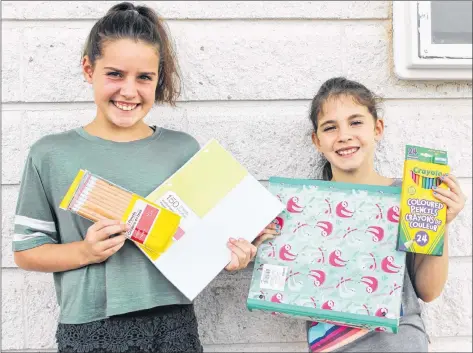  ?? KATHERINE HUNT/THE GUARDIAN ?? Olivia Roche, left, and her sister Charlotte hold up some of the school supplies Olivia will have to take to Donagh Regional School this Thursday.