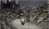  ?? SHIZUO KAMBAYASHI — THE ASSOCIATED PRESS FILE ?? A man rides his motorcycle on a makeshift road amid rubble in Rikuzentak­ata, Iwate Prefecture, northern Japan, on March 20, 2011. On March 11 of that year, an earthquake and tsunami devastated the area.