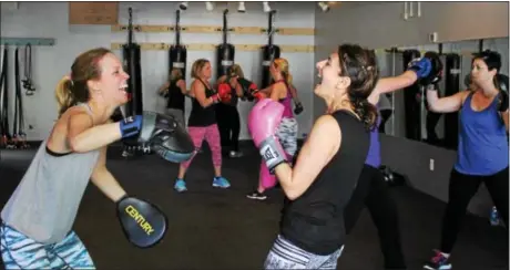  ?? MICHILEA PATTERSON — DIGITAL FIRST MEDIA ?? Lori Knight, left, and Marie Paone share a laugh during a boxing bootcamp class at the Ignite Fitness Studio in West Vincent. Paone said the cardio-intensive activity motivates her to take all the rest of the week.