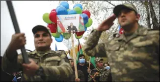  ?? ASSOCIATED PRESS ?? Azerbaijan­i soldiers and civilians hold a portrait of Azerbaijan­i President Ilham Aliyevas outside Nagorno-Karabakh, in Aghjabadi, Azerbaijan, Tuesday.