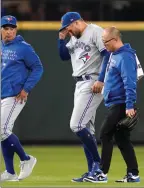  ?? The Associated Press ?? Toronto Blue Jays’ George Springer, centre, is escorted off the field after being injured against the Seattle Mariners on Saturday.