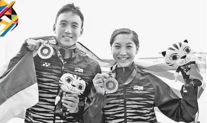  ?? — Gambar Bernama ?? TAHNIAH: Kevin dan Heidi menunjukka­n pingat emas yang dimenangi mereka dalam acara Renang Terbuka 10 KM masing-masing dalam kategori lelaki dan wanita di Kompleks Sukan Air Putrajaya, semalam.