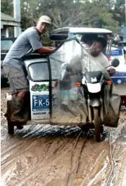  ?? GRIG C. MONTEGRAND­E ?? A TRICYCLE negotiates a muddy road in Cabanatuan City on Oct. 20 as floodwater­s brought by Typhoon “Lando” (internatio­nal name: Koppu) subside.