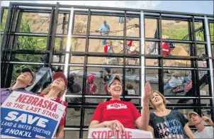  ?? AP PHOTO/NATI HARNIK ?? In this July 29 photo, Jane Kleeb, president of Bold Alliance, center, landowner Chris Carlson, second right, and volunteers, pose for a photo under an array of solar panels they built in a corn field belonging to the Carlsons of Silver Creek, Ne., in...