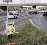  ?? RALPH BARRERA / AMERICAN-STATESMAN ?? Workers remove a “merge” sign from the shoulder of the southbound entrance ramp onto I-35 near Oltorf Street, an area where old striping and new striping confused motorists.