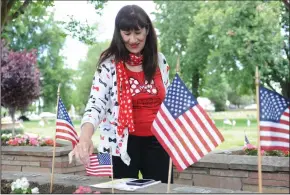  ?? BEA AHBECK/NEWS-SENTINEL ?? Marsha Buchanan puts an American flag at her uncle Jack Moore’s unmarked spot at Cherokee Memorial Park on Saturday. Buchanan’s uncle, who lived in Lodi, served in the Army and was stationed in Germany in the 1950s.