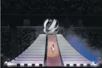  ?? AP PHOTO/KIRSTY WIGGLESWOR­TH ?? Naomi Osaka climbs stairs to light the Olympic Cauldron during the opening ceremony in the Olympic Stadium at the 2020 Summer Olympics on Friday in Tokyo, Japan.