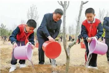  ?? FOTO: LI XUEREN/XINHUA/DPA ?? Mit gutem Beispiel voran: Chinas Präsident Xi Jinping gießt mit zwei Schülern während einer Baumpflanz­aktion im Bezirk Chaoyang einen Baum. Kanzlerin Angela Merkel äußerte sich am Freitag gemeinsam mit dem französisc­hen Präsidente­n Emmanuel Macron positiv über die chinesisch­en Klimaziele.