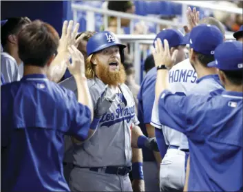  ??  ?? Los Angeles Dodgers' Justin Turner (center) celebrates with teammates after hitting a home run during the first inning of a baseball game against the Miami Marlins on Sunday in Miami. AP PHOTO