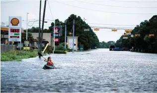  ??  ?? A woman paddles down a flooded road while making deliveries for her neighbours in Houston on Wednesday.