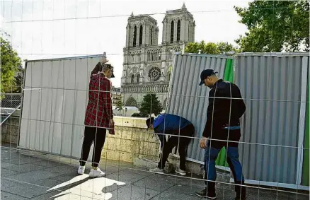  ?? Bertrand Guay - 13.ago.19/AFP ?? Funcionári­os instalam tapumes para isolar a área da catedral para descontami­nação
