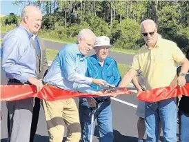  ?? JERRY FALLSTROM/ORLANDO SENTINEL ?? A ribbon-cutting ceremony takes place Wednesday to mark the opening of the new Citrus Grove Road in Minneola. From left are Lake County Commission­er Tim Sullivan, Commission­er Sean Parks, Minneola resident Charlie Foss and Minneola Mayor Pat Kelley.