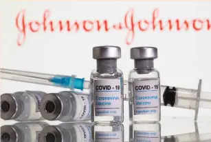  ?? (Dado Ruvic/Reuters) ?? VIALS LABELED ‘COVID-19 Coronaviru­s Vaccine’ and a syringe are seen in front of displayed Johnson&Johnson logo.