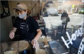  ?? AP PHOTO/MARCIO JOSE SANCHEZ ?? Hannah Smith, left, prepares food for a customer waiting outside of Quesadilla Gorilla Wednesday, in Visalia, Calif.