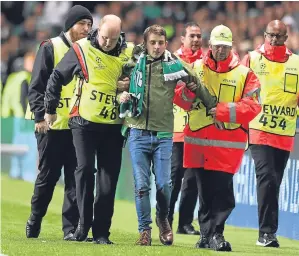  ??  ?? Led away: A supporter is taken away after his pitch invasion at Parkhead