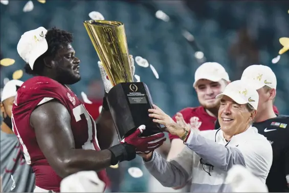  ?? AP photos ?? Alabama head coach Nick Saban and offensive lineman Alex Leatherwoo­d hold the trophy after the Crimson Tide’s 52-24 victory over Ohio State in the College Football Playoff national championsh­ip game Monday. It is Saban’s sixth national title with Alabama, and seventh overall.