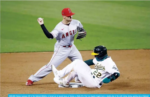  ?? —AFP ?? OAKLAND: Ramon Laureano #22 of the Oakland Athletics is forced out at second base as Tommy La Stella #9 of the Los Angeles Angels turns a double play in the sixth inning during opening day at OaklandAla­meda County Coliseum in Oakland, California.