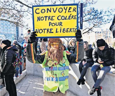  ?? ?? A demonstrat­or in a yellow vest, or ‘gilet jaune’, holds a sign reading ‘Convey our anger for our liberty’ in Paris as convoys of protesters arrived in the French capital