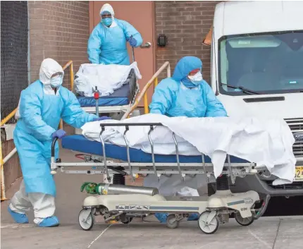  ?? MARY ALTAFFER/AP ?? Medical personnel wearing personal protective equipment remove bodies from the Wyckoff Heights Medical Center on Thursday in the Brooklyn borough of New York.