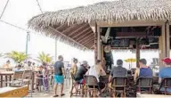  ??  ?? The patio of popular restaurant and bar Coconuts on the Beach is crowded with visitors during Monday’s lunchtime.