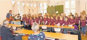  ??  ?? Raimund Haser begleitet in der Grundschul­e Haisterkir­ch den Chor mit der Gitarre.