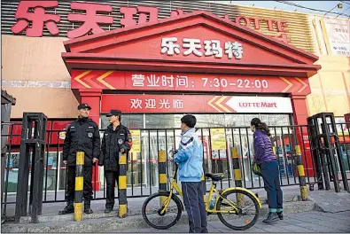  ?? AP ?? In March, Chinese security officials stand outside a Lotte supermarke­t that was closed under orders from Beijing’s Fire department after the South Korean retailer ran afoul of the government.