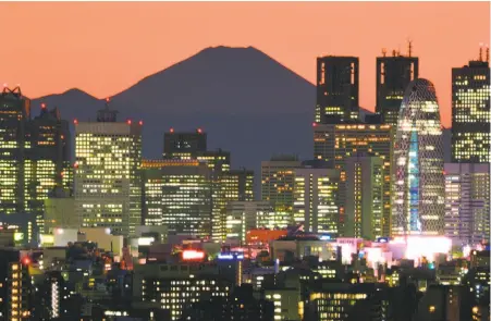  ?? Kazuhiro Nogi / AFP / Getty Images ?? Mount Fuji, Japan’s highest mountain, dominates the skyline of the Shinjuku area of Tokyo at sunset. A traveler who booked a hotel in Tokyo and later canceled the reservatio­n learned the deadline for a cancellati­on refund was not based on her local time.