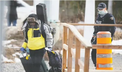  ?? Christine Muschi / Reuters Files ?? An asylum-seeker crosses the border from New York into Canada followed by an RCMP officer on March 18,
just days before tight coronaviru­s restrictio­ns came into effect on March 21.