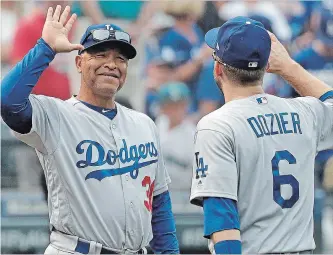  ?? ASSOCIATED PRESS FILE PHOTO ?? Los Angeles Dodgers manager Dave Roberts, left, reacts as he greets Brian Dozier after they defeated the Mariners in Seattle on Aug. 19. A long-term contract will keep Roberts at the helm through 2022.