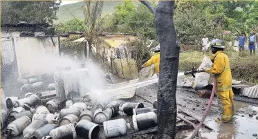  ?? PHOTOS BY NORMAN GRINDLEY/CHIEF PHOTOGRAPH­ER ?? A firefighte­r carries out cooling-down operations at a local cooking gas operation behind a home on Jacques Avenue in Mountain View, St Andrew, yesterday.