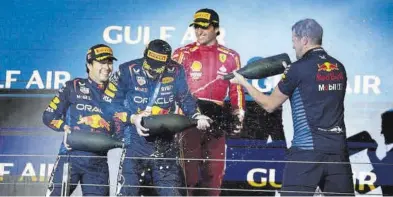  ?? DARKO BANDIC / AP ?? Verstappen y Pérez se duchan en champán bajo la mirada de Carlos Sainz, ayer en el podio