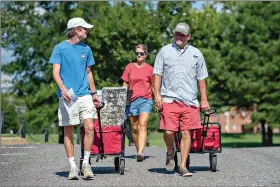  ??  ?? Baylor Garland, left, of Eaton, Ga., arrives to move in for his freshman year — assisted by his father Alan, right and mother, Teena — Saturday at the University of Alabama in Tuscaloosa. More than 20,000 students returned to campus for the first time since spring break with numerous school and city codes in effect to limit the spread of COVID-19. (AP Photo/Vasha Hunt)