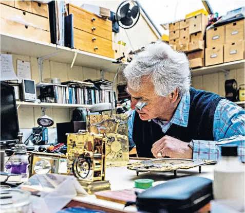  ?? ?? Mark Sampson, a clock restorer, examines a vintage timepiece in his workshop in Cirenceste­r. He said there were precious few people coming into the business