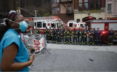  ?? AP FILE PHOTOS ?? GIVING THEM A HAND: FDNY firefighte­rs gather to applaud medical workers as attending physician Mollie Williams, left, stands outside Brooklyn Hospital Center in New York in April. Below, medical personnel attend a daily applause in their honor outside NYU Langone Medical Center in Manhattan.