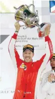  ?? — Reuters ?? Ferrari’s Sebastian Vettel celebrates winning the race with the trophy.