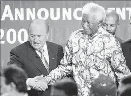  ?? Michael Probst
Associated Press ?? IN 2004, FIFA chief Sepp Blatter congratula­tes former South African President Nelson Mandela after Mandela’s country was chosen to host the 2010 World Cup.