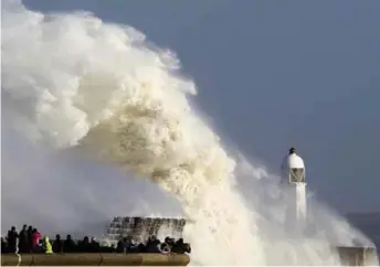  ??  ?? Huge waves strike the harbour wall and lighthouse at Porthcawl, south Wales, on Monday as Ophelia hits the UK and Ireland.