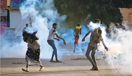  ?? AFP VIA GETTY IMAGES ?? Protesters take cover as security forces use tear gas to disperse the crowd in the capital of Khartoum, Sudan, on Wednesday amid ongoing demonstrat­ions against a military takeover that has sparked widespread internatio­nal condemnati­on.