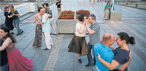  ?? REBECCA BLACKWELL/THE ASSOCIATED PRESS ?? New books on dancing could inspire you to “twist and shout” like these couples dancing the tango on a Moscow bridge to mark the World Cup.