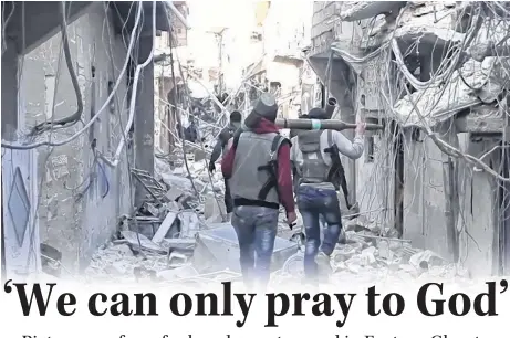  ??  ?? TOP PHOTO Armed Syrian rebels walk through a rubble-strewn part of Damascus. (Wikimedia photo)