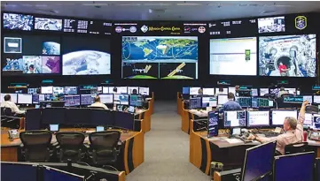  ?? Jon Shapley/Houston Chronicle via AP ?? Timothy “T.J.” Creamer, right, a former astronaut and current mission control flight director at NASA, works April 27 in the mission control room at the Johnson Space Center in Houston.