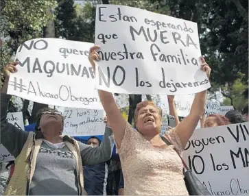  ?? Rebecca Blackwell Associated Press ?? FAMILY MEMBERS hold signs that read in Spanish “They are waiting for our family to die,” “They are still alive; don’t kill them” and “No heavy machinery” on Friday in Mexico City’s Roma Norte neighborho­od.